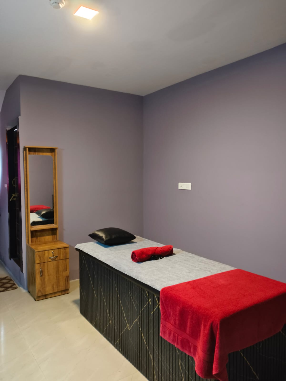Private massage room with treatment bed and red towels